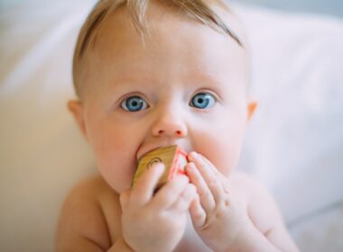 selective focus photography of baby holding wooden cube